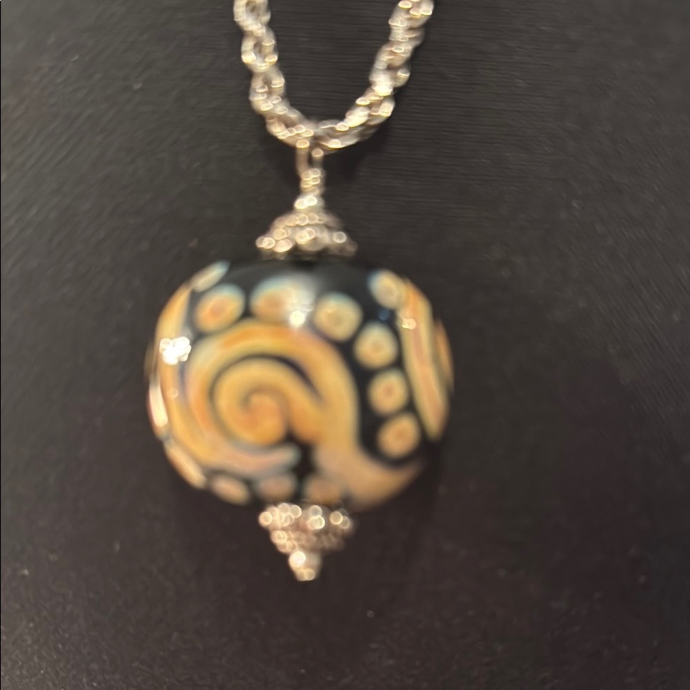 Intricate Black and Gold Swirl Pendant Necklace with a silver chain.